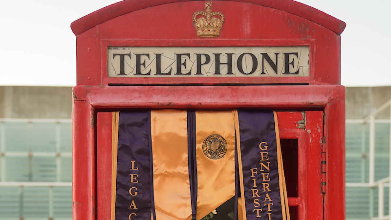 Phone booth with commencement banners draped over door.