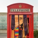 Phone booth with commencement banners draped over door.