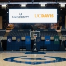 The interior of the Pavilion, featuring basketball hoops, seating and a large digital display board that says University Credit Union and UC Davis